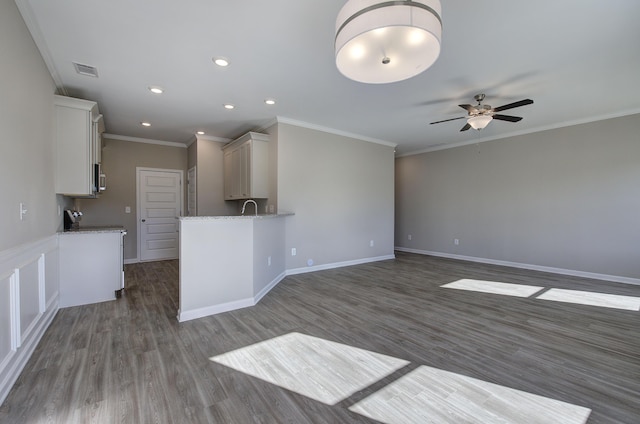 unfurnished living room with ceiling fan, sink, crown molding, and dark wood-type flooring