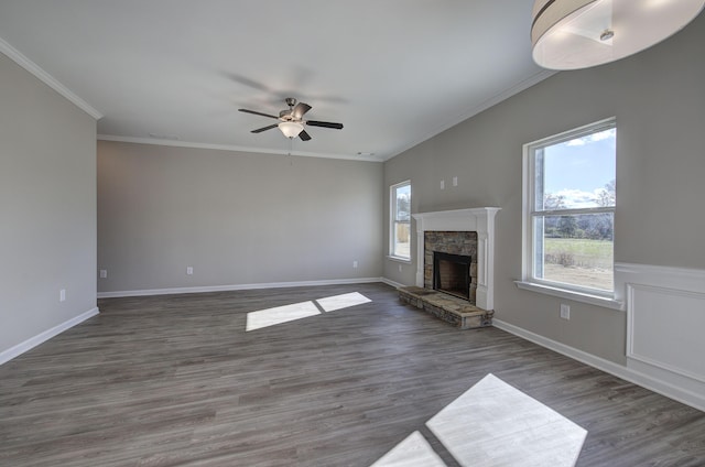 unfurnished living room featuring a stone fireplace, ceiling fan, dark wood-type flooring, and ornamental molding