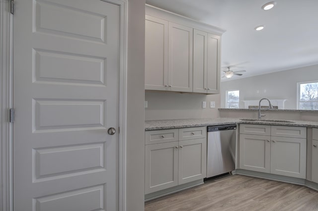 kitchen with dishwasher, sink, light hardwood / wood-style flooring, ceiling fan, and light stone countertops