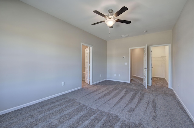 unfurnished bedroom with carpet flooring, ensuite bath, ceiling fan, a walk in closet, and a closet