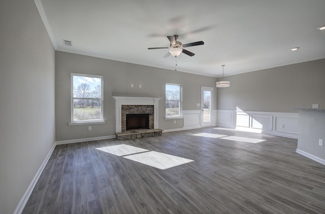 unfurnished living room with ceiling fan, a stone fireplace, dark hardwood / wood-style flooring, and crown molding