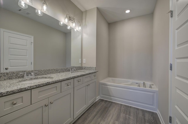 bathroom featuring hardwood / wood-style floors, vanity, and a tub to relax in