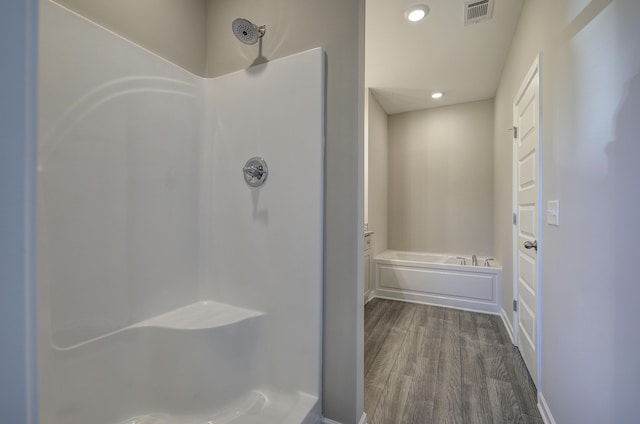 bathroom featuring wood-type flooring and shower with separate bathtub