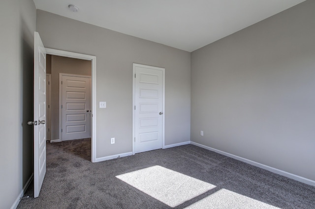 unfurnished bedroom with dark carpet and a closet