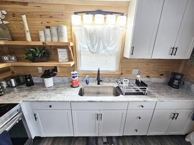 kitchen featuring white cabinetry, sink, light stone countertops, dark wood-type flooring, and stainless steel range with electric stovetop