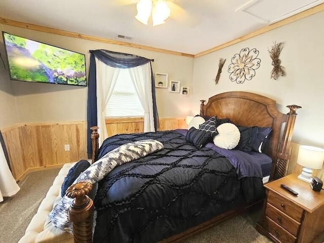 carpeted bedroom with ceiling fan, wooden walls, and ornamental molding