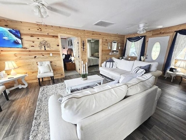 living room with wooden walls, dark hardwood / wood-style flooring, and ceiling fan