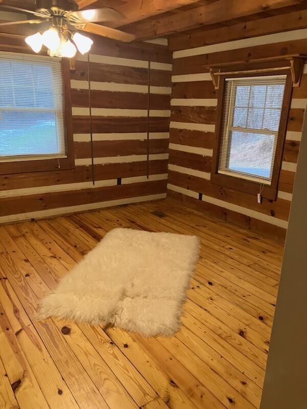 interior space featuring ceiling fan, hardwood / wood-style floors, and wooden walls