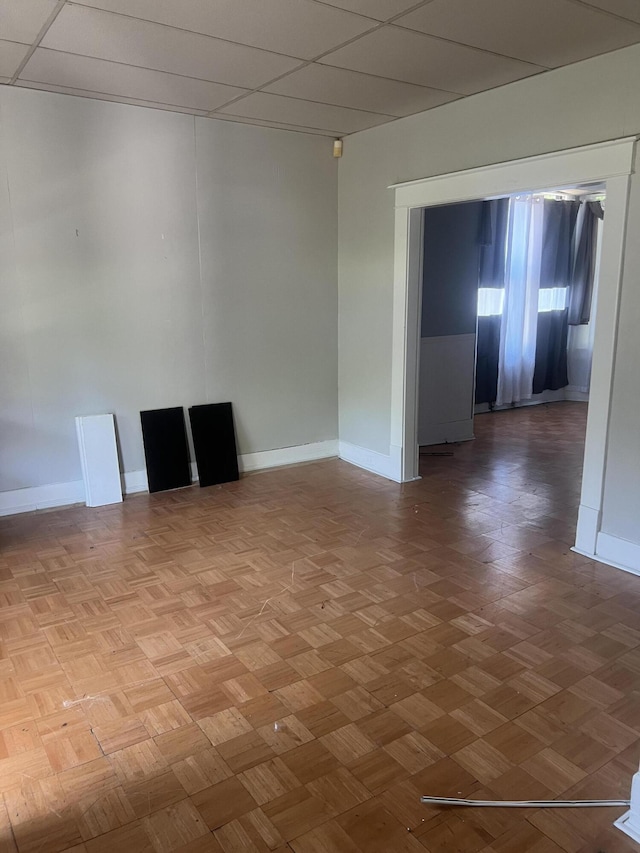 empty room featuring a paneled ceiling and parquet flooring