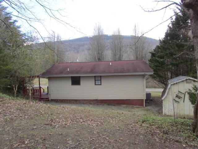 view of side of home with a mountain view and a storage shed