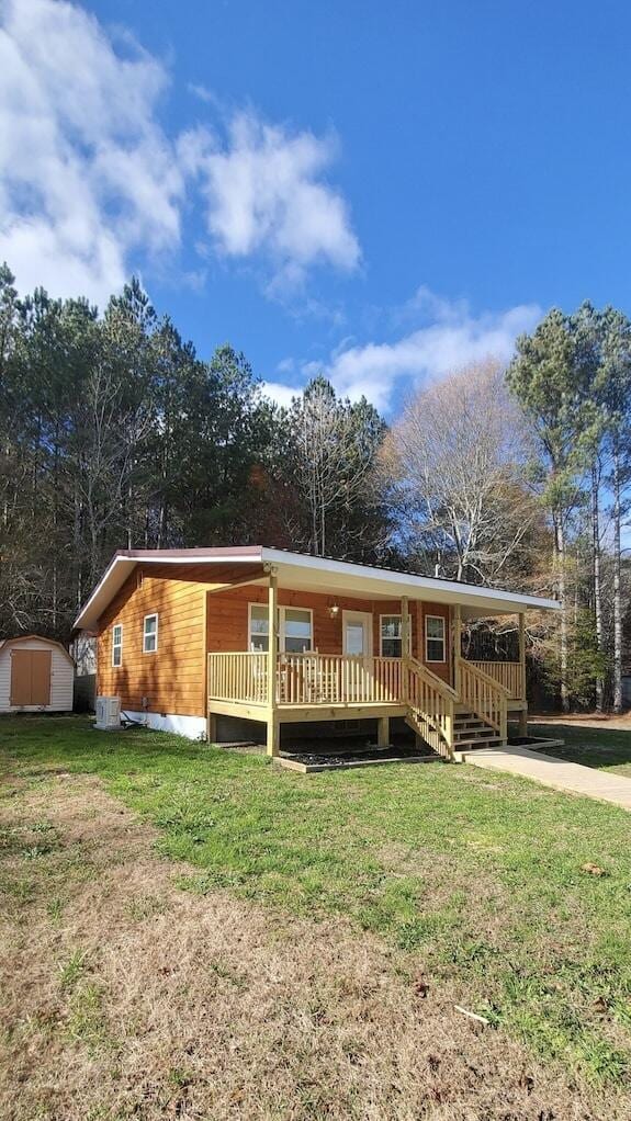 view of front of property with a shed, a deck, and a front lawn