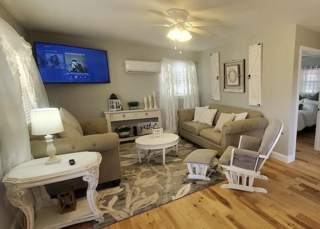 living room featuring light hardwood / wood-style floors, a wall unit AC, and ceiling fan