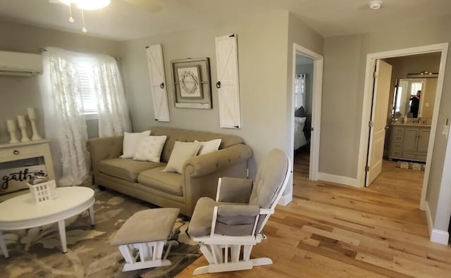 sitting room with light hardwood / wood-style floors, a wall unit AC, and ceiling fan