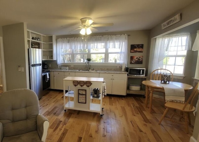 kitchen featuring sink, white cabinetry, stainless steel appliances, and light hardwood / wood-style flooring