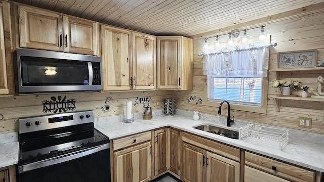 kitchen featuring wood walls, wooden ceiling, sink, appliances with stainless steel finishes, and light stone counters