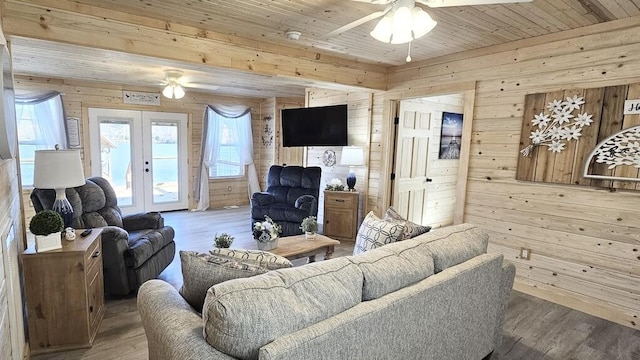 living room featuring hardwood / wood-style floors, wood walls, wooden ceiling, french doors, and ceiling fan