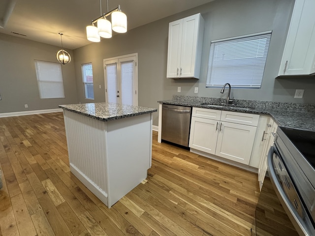 kitchen featuring sink, appliances with stainless steel finishes, decorative light fixtures, light hardwood / wood-style floors, and white cabinetry