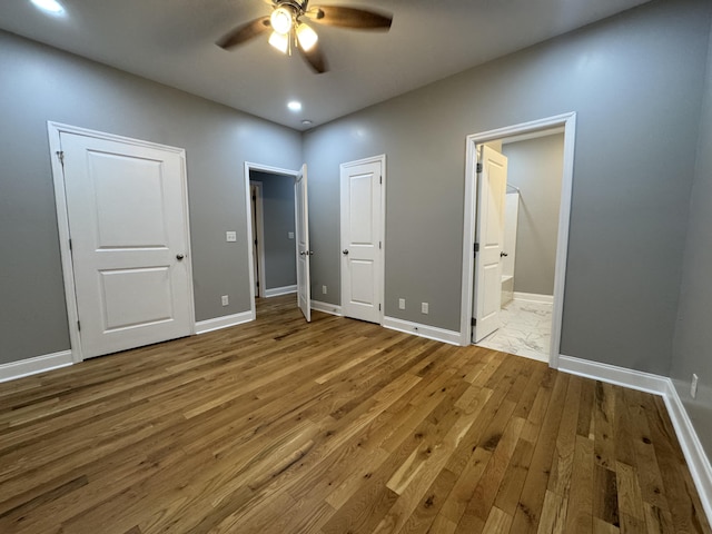 unfurnished bedroom with connected bathroom, hardwood / wood-style flooring, and ceiling fan