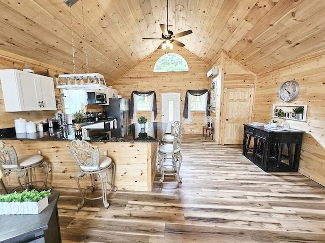 kitchen with a kitchen bar, wooden ceiling, light wood-type flooring, and appliances with stainless steel finishes