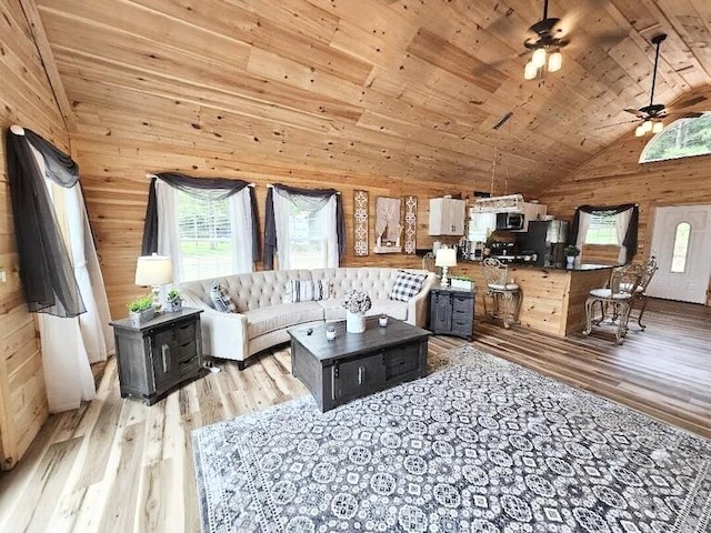 living room with light hardwood / wood-style flooring, ceiling fan, wooden walls, and wood ceiling