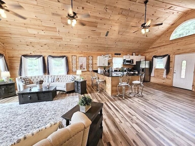 living room featuring wood ceiling, wood walls, high vaulted ceiling, and light hardwood / wood-style floors