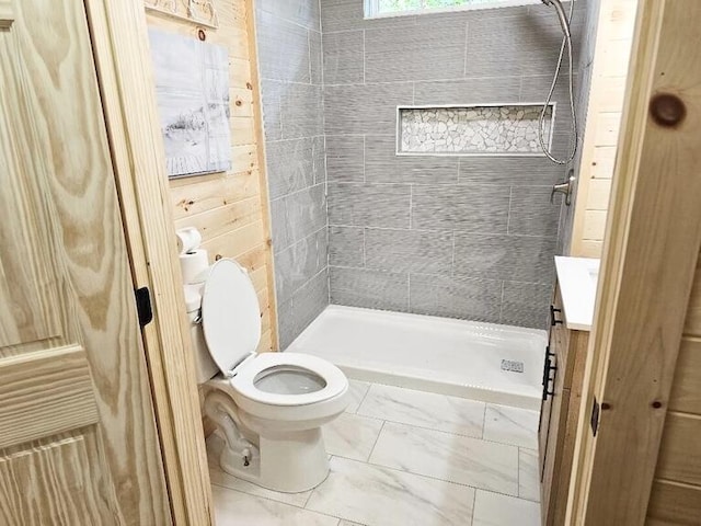 bathroom featuring a tile shower, vanity, and toilet