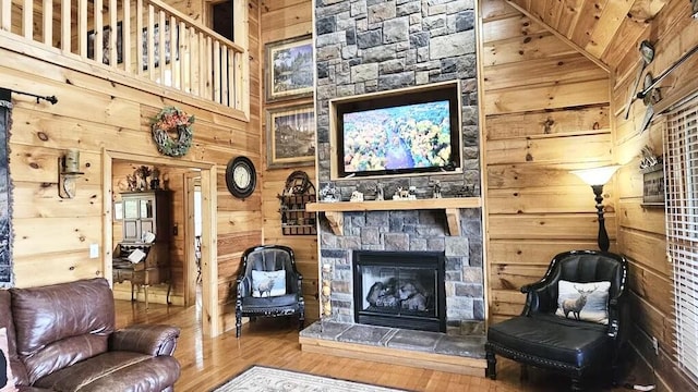 living room with wood-type flooring, high vaulted ceiling, a stone fireplace, and wooden ceiling