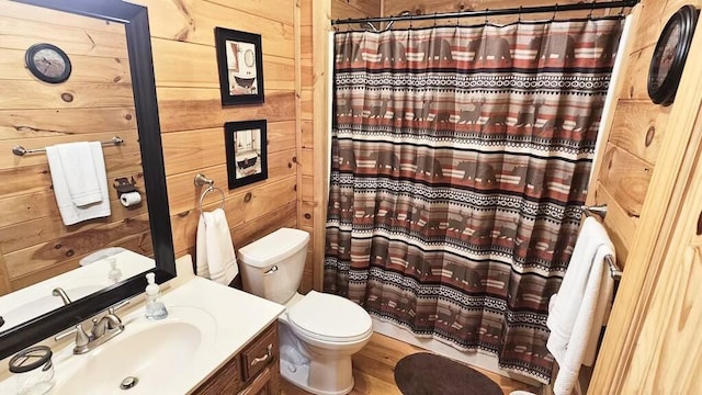 bathroom with curtained shower, wooden walls, vanity, and toilet