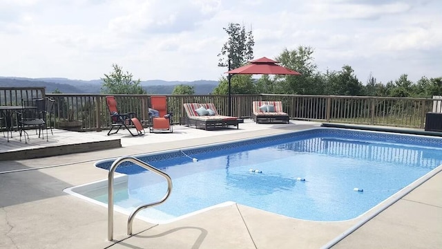 view of swimming pool featuring a patio area and a deck with mountain view