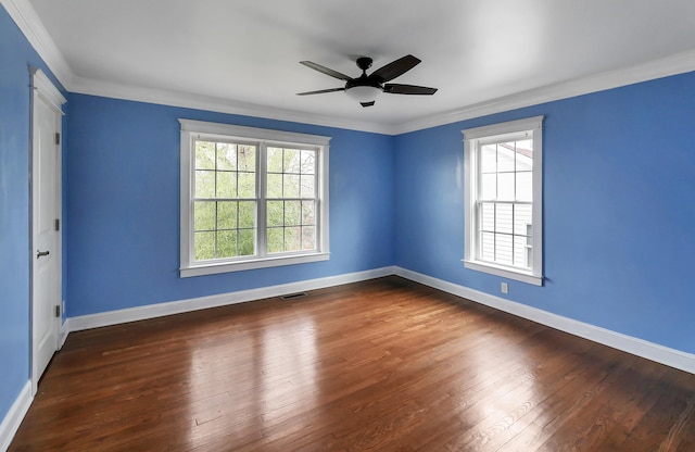 empty room with plenty of natural light, dark hardwood / wood-style floors, and crown molding