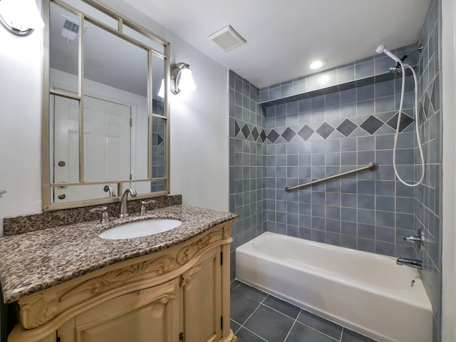 bathroom with tile patterned flooring, vanity, and tiled shower / bath