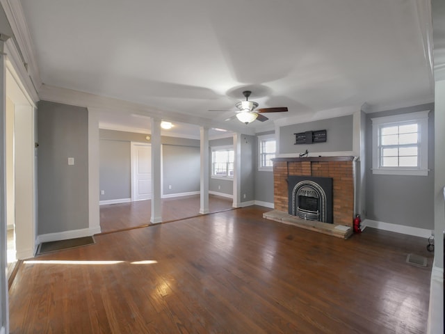 unfurnished living room with decorative columns, a brick fireplace, ceiling fan, crown molding, and hardwood / wood-style flooring