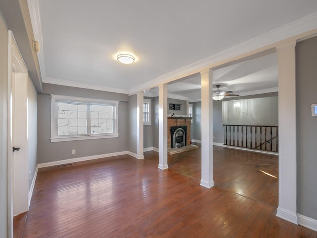 unfurnished living room featuring ceiling fan, dark hardwood / wood-style flooring, crown molding, and a brick fireplace