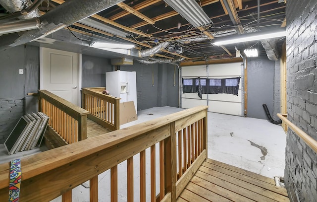 basement featuring white refrigerator with ice dispenser