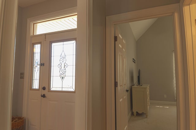 foyer entrance with carpet floors, vaulted ceiling, and plenty of natural light