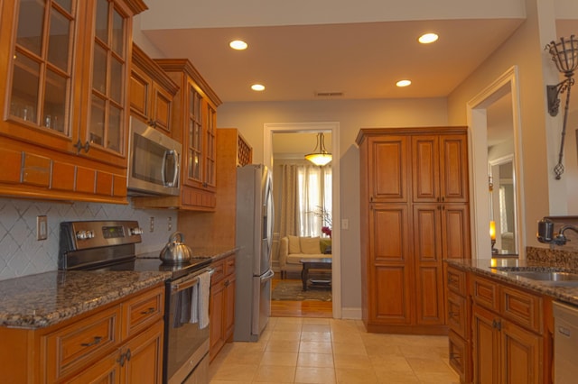 kitchen with decorative backsplash, sink, appliances with stainless steel finishes, and dark stone counters