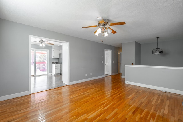 unfurnished living room with a textured ceiling, light wood-type flooring, and ceiling fan