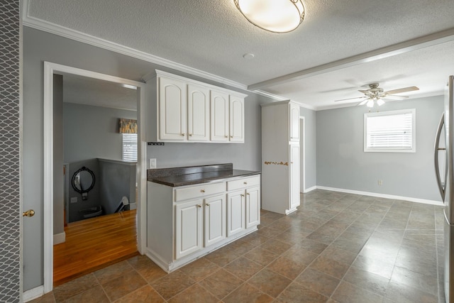 kitchen with stainless steel refrigerator, ceiling fan, crown molding, a textured ceiling, and white cabinets