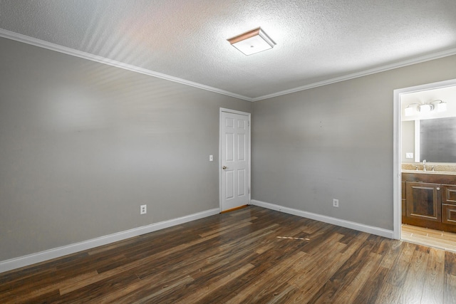 unfurnished room featuring a textured ceiling, crown molding, sink, and dark wood-type flooring