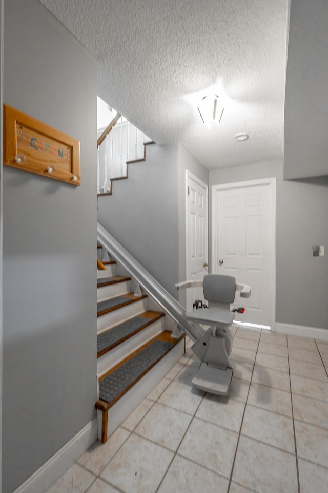 stairs with a textured ceiling and tile patterned floors