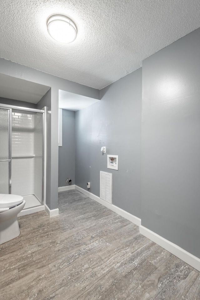 laundry area with hardwood / wood-style flooring, a textured ceiling, and washer hookup