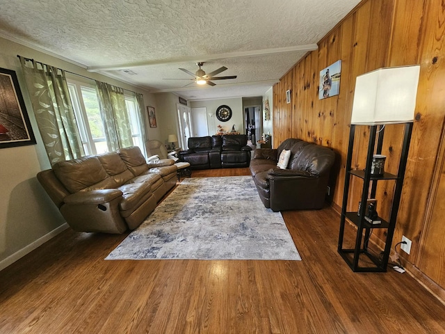 living room featuring dark hardwood / wood-style floors, wood walls, a textured ceiling, and ceiling fan