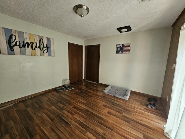 unfurnished bedroom with a textured ceiling and dark wood-type flooring