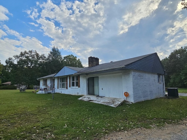 rear view of property featuring a yard and central air condition unit