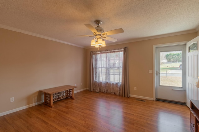 empty room featuring a textured ceiling, ceiling fan, light hardwood / wood-style floors, and crown molding