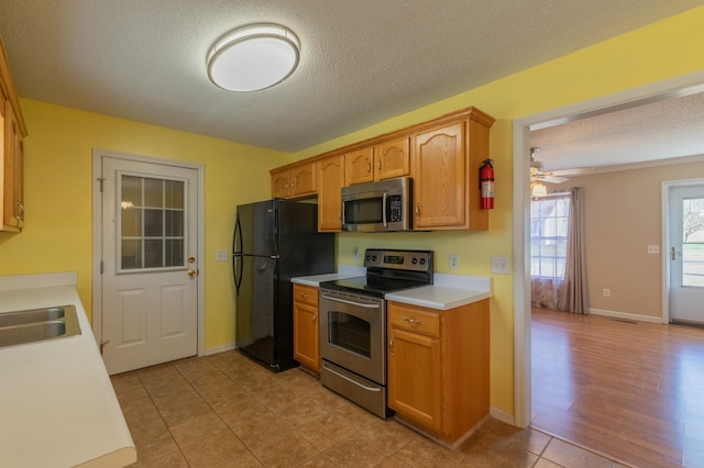 kitchen with sink, a textured ceiling, ceiling fan, light tile patterned floors, and appliances with stainless steel finishes