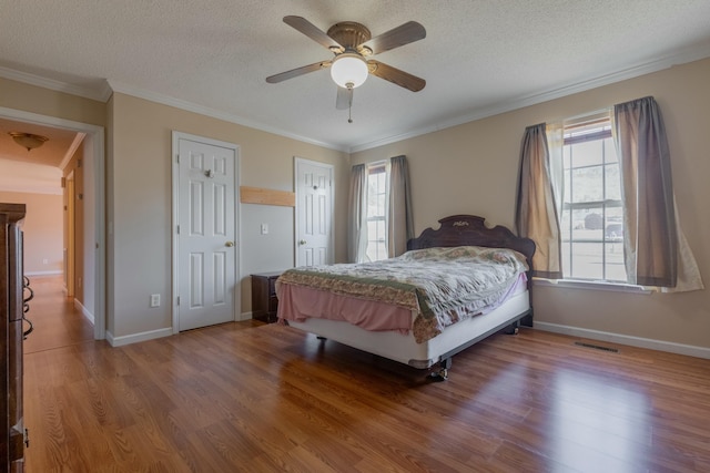 bedroom featuring wood-type flooring, a textured ceiling, ceiling fan, and crown molding