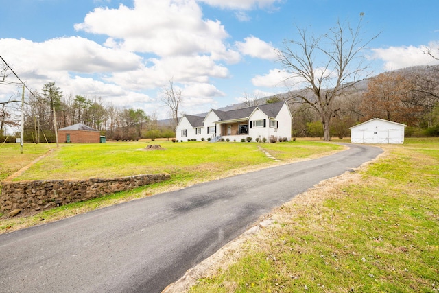 view of front of home featuring a garage, an outdoor structure, and a front lawn