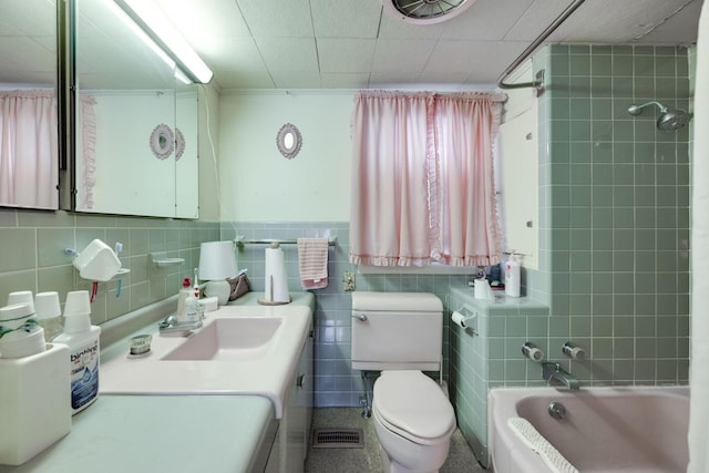 full bathroom featuring vanity, toilet, tiled shower / bath, and tile walls