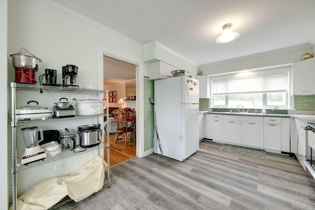 kitchen with white cabinets, light hardwood / wood-style flooring, and white fridge